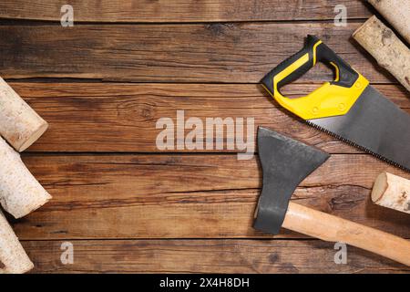 Scie avec poignée jaune, hache et bois de chauffage sur fond en bois, pose plate. Espace pour le texte Banque D'Images
