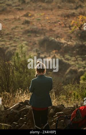 contempler le vaste paysage : jeune femme se tient dos au spectateur, absorbant la tranquillité de la nature par une journée ensoleillée Banque D'Images