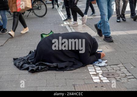 Eine schwarz gekleidete Bettlerin kniet mit gesenktem Kopf und zusammengelegten Händen in der Offenbacher Fußgängerzone Frankfurter Straße, während Passanten an ihr vorbeigehen Offenbach am main Hessen Deutschland *** Une mendiante vêtue de genoux noirs, la tête courbée et les mains serrées ensemble dans la zone piétonne Offenbachs Frankfurter Straße tandis que les passants passent devant son Offenbach am main Hesse Allemagne Banque D'Images