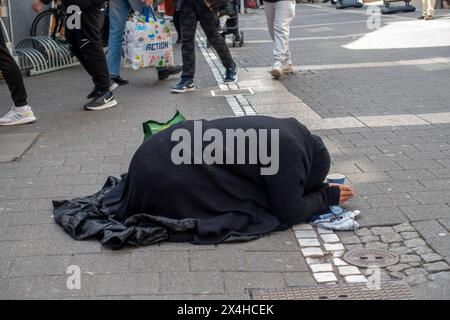 Eine schwarz gekleidete Bettlerin kniet mit gesenktem Kopf und zusammengelegten Händen in der Offenbacher Fußgängerzone Frankfurter Straße, während Passanten an ihr vorbeigehen Offenbach am main Hessen Deutschland *** Une mendiante vêtue de genoux noirs, la tête courbée et les mains serrées ensemble dans la zone piétonne Offenbachs Frankfurter Straße tandis que les passants passent devant son Offenbach am main Hesse Allemagne Banque D'Images