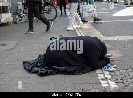 Eine schwarz gekleidete Bettlerin kniet mit gesenktem Kopf und zusammengelegten Händen in der Offenbacher Fußgängerzone Frankfurter Straße, während Passanten an ihr vorbeigehen Offenbach am main Hessen Deutschland *** Une mendiante vêtue de genoux noirs, la tête courbée et les mains serrées ensemble dans la zone piétonne Offenbachs Frankfurter Straße tandis que les passants passent devant son Offenbach am main Hesse Allemagne Banque D'Images