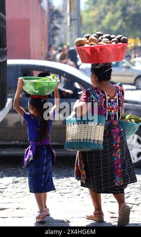 Mère maya autochtone et enfant mis au marché. Tous deux en costume indigène, portant des produits dans des bols sur leurs têtes, Antigua, Guatemala, Amérique centrale Banque D'Images