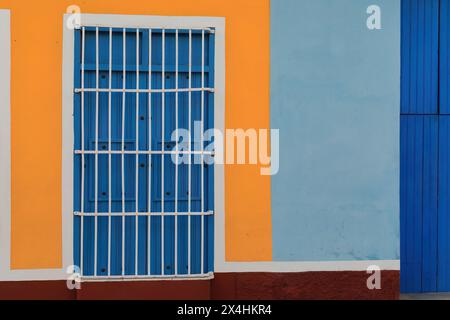 230 mur coloriste de la maison coloniale montrant la fenêtre habituelle, à volets en bois, longue grille comme une porte sur la façade bleu-orange-marron-blanc. Trinidad-Cuba. Banque D'Images