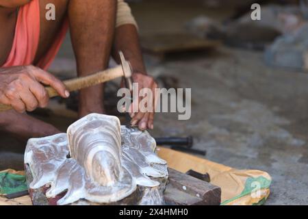 Un artisan indien qualifié façonnant le métal pour créer une idole religieuse dans son atelier. Banque D'Images