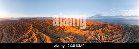 Canyon traverse le paysage, Issyk Kul Lake, derrière les sommets blancs des montagnes Tien Shan, paysage aride dramatique de collines érodées, Badlands Banque D'Images