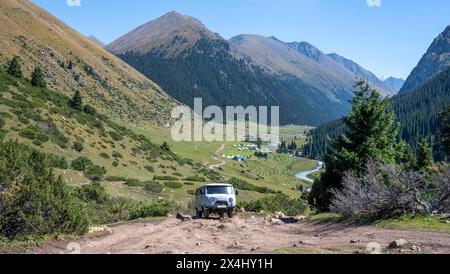 UAZ Buchanka, véhicule tout-terrain russe sur piste 4x4, vallée de montagne verte avec village Altyn Arashan, montagnes Tien Shan, Kirghizistan Banque D'Images