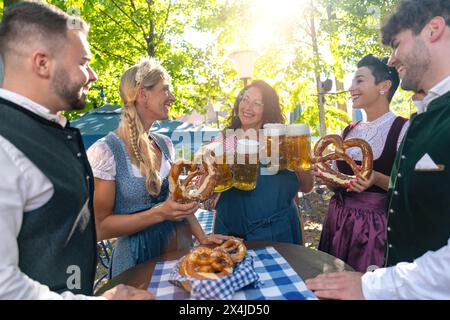 Serveuse servant de la bière à un groupe d'amis heureux dans le tracht traditionnel à l'oktoberfest ou au jardin de bière en allemagne Banque D'Images
