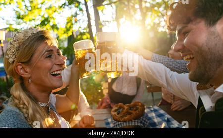 Groupe d'amis dans le jardin de la bière griller avec des tasses à bière en été Banque D'Images