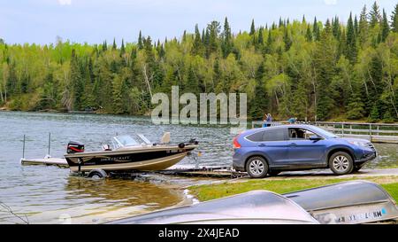 CLEARWATER CO, MN - 23 MAI 2020 : bateau de pêche avec moteur hors-bord sur une remorque est tiré hors de l'eau par une automobile sur un lac du Minnesota. Banque D'Images