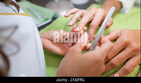 Manucure appliquant le traitement aux ongles du client dans un salon de manucure Banque D'Images