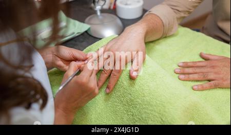 la manucure avec un poussoir élimine les callosités de l'ongle d'un client. image du concept de soin spa de soins corporels Banque D'Images