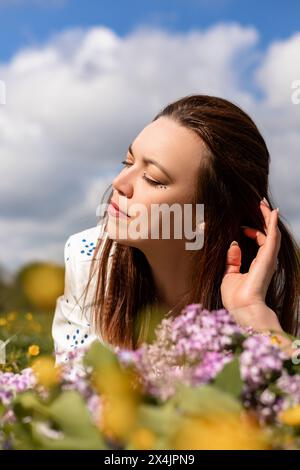 Détendue belle femme couchée dans l'herbe avec ses yeux fermés. Loisirs en plein air. Photo de haute qualité Banque D'Images