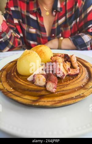 Savourez la saveur unique du poulpe tendre servi avec des pommes de terre sur une assiette en bois pour les amateurs de gastronomie. Banque D'Images