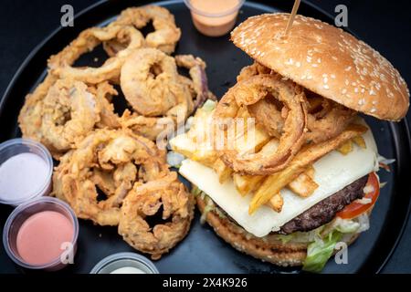 Sandwich burguer au fromage avec frites sur papier avec fond noir Banque D'Images