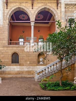 La cour sereine met en valeur la beauté intemporelle de l'architecture mamelouk avec de grandes arches et des pierres avec escalier accueillant menant à un balcon orné Banque D'Images