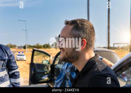 homme blanc avec des lunettes devant la voiture sur le bord de la route, policier et voiture de police à proximité, en attente d'assistance, en afrique du sud Banque D'Images