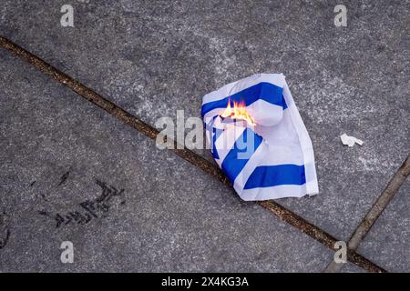 New York, États-Unis. 03 mai 2024. Les manifestants brûlent un petit drapeau israélien pendant la manifestation. Les groupes étudiants pro-palestiniens continuent de manifester à New York. Après que le NYPD eut nettoyé les campements à la fois à la NYU et à la New School tôt vendredi matin, les étudiants se sont rassemblés au Paulson Center de NYU, ont marché vers la New School, puis vers le Washington Square Park. La marche a été organisée par Shut It Down for Palestine, une coalition d'organisations exigeant un cessez-le-feu et la réduction de l'aide à Israël. Crédit : SOPA images Limited/Alamy Live News Banque D'Images