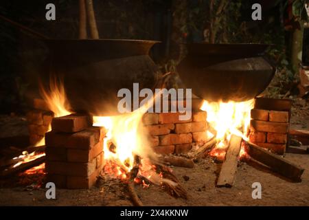 Biryani cuisine dans une fête de village sur un four en briques temporaire. Cuisine extérieure pour beaucoup de gens dans une grande casserole en aluminium au feu de bois. cuisine énorme Banque D'Images