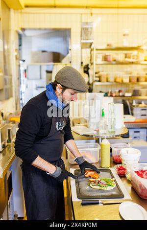 Freiamt, Allemagne. 04 mai 2024. Michael Wickert prépare un rouleau de poisson avec du saumon fumé lors de la Journée mondiale du rouleau de poisson d'aujourd'hui. Le rouleau de poisson a commencé par un simple hareng Bismarck entre deux moitiés du rouleau. Depuis, matjes, hareng frit, rollmops, saumon, maquereau, filets de poisson frits et gâteaux de poisson ont également trouvé leur chemin dans le rouleau de poisson. Wickert dirige le fumoir de poisson 'Glut & Späne' à Freiamt, Baden. Crédit : Philipp von Ditfurth/dpa/Alamy Live News Banque D'Images