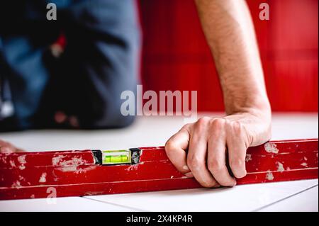 Gros plan d'un entrepreneur d'intérieur blanc masculin du Caucase à l'aide d'un niveau à bulle sur le sol Banque D'Images