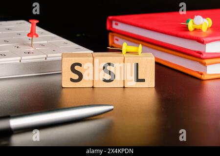 SSL - Secure Sockets Layer écrit sur des cubes en bois sur un fond noir dans une composition avec une calculatrice, des cahiers et un stylo Banque D'Images