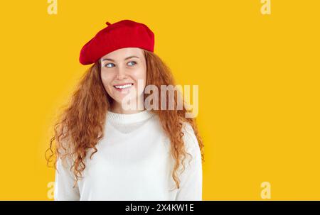 Portrait de belle fille heureuse avec les cheveux longs ondulés rouges regarde loin et sourit avec le sourire dentaire blanc neige. Banque D'Images