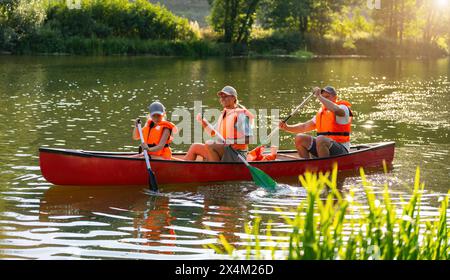 Famille de trois canoë sur une rivière calme à l'été mère et fille pagayant à l'avant, père à l'arrière en allemagne. Famille en kayak. Sauvage na Banque D'Images