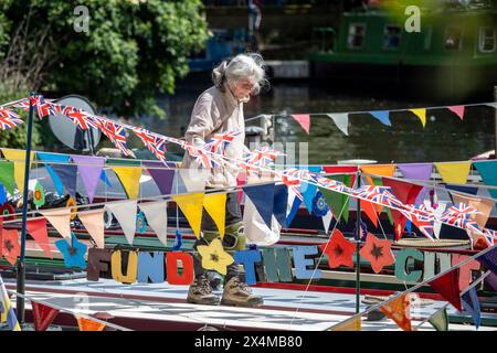 Londres, Royaume-Uni. 4 mai 2024. Un propriétaire décorant son bateau étroit avec des banderoles colorées et d'autres décorations de style festival pendant la Canalway Cavalcade de l'Inland Waterways Association (IWA) à Little Venice pour célébrer le meilleur de la vie sur les voies navigables de Londres et sa communauté. L'événement se déroule au cours du week-end des fêtes bancaires de début mai et célèbre son 41e anniversaire cette année. Credit : Stephen Chung / Alamy Live News Banque D'Images