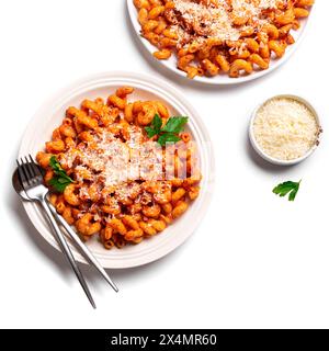 Pâtes cavatappi avec sauce tomate et fromage parmesan râpé isolé sur fond blanc. Pâtes végétariennes servies sur deux assiettes et bol de parmesan. Banque D'Images