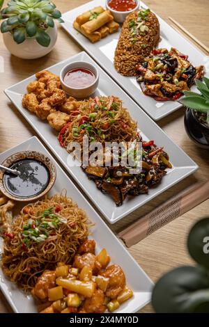 Vue aérienne de divers plats asiatiques, y compris nouilles et boulettes servies sur une table en bois Banque D'Images