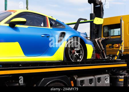 Sport rapide super voiture course auto compétition cassé après accident chargé sur le service de sécurité de dépanneuse sur la journée ensoleillée brillante. Assistance au défi Banque D'Images