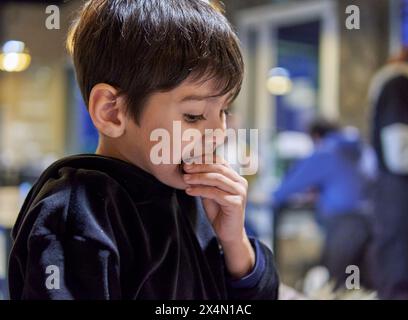 portrait d'un garçon latin mangeant un cookie pour le petit déjeuner dans un bar argentin. mise au point sélective Banque D'Images