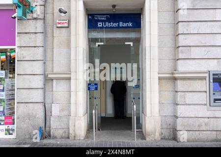 DUBLIN, IRLANDE - 26 MARS 2023 : un homme retire de l'argent d'un distributeur automatique de billets à l'entrée d'une succursale de l'Ulster Bank en Irlande. Banque D'Images