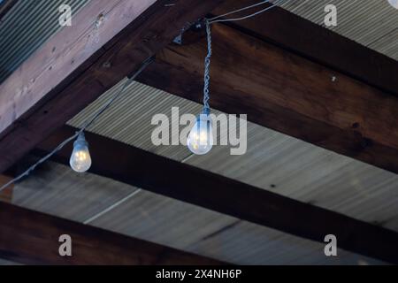 Une chaîne de lumières est suspendue à une poutre en bois robuste, ajoutant une ambiance chaleureuse à la zone ombragée ci-dessous. La structure en bois dur est accentuée avec WO Banque D'Images