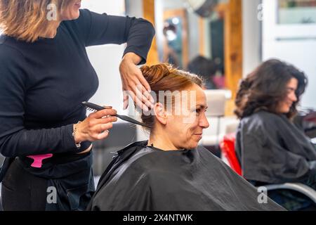 Vue de côté et photo recadrée d'un coiffeur méconnaissable faisant un chignon élégant pour un client Banque D'Images