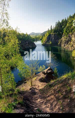 chemin menant à un gros rocher au-dessus d'une carrière remplie d'eau Banque D'Images