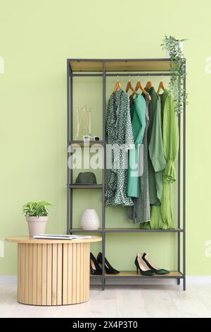 Rack avec vêtements féminins élégants, chaussures et accessoires près du mur de couleur dans la chambre Banque D'Images