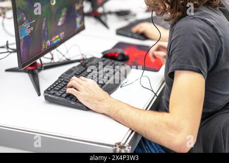 Jeune joueur méconnaissable jouant à un jeu vidéo informatique en ligne. Concept de dépendance aux jeux vidéo. Banque D'Images