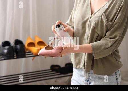 Femme appliquant un spray hydrofuge sur les chaussures à la maison Banque D'Images