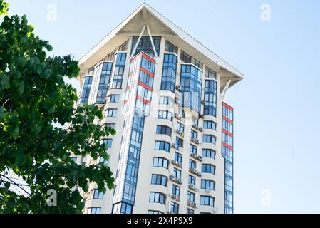 super moderne immeuble résidentiel de grande hauteur avec arbre vert sur fond de ciel bleu. Banque D'Images