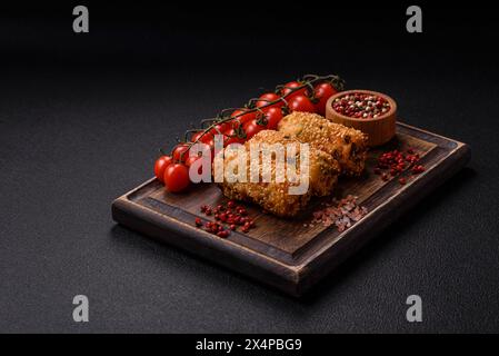 Délicieux plat végétarien ou végétalien copieux sous forme de côtelettes ou de galettes composées de pommes de terre, carottes, oignons et haricots sur un fond en béton sombre Banque D'Images