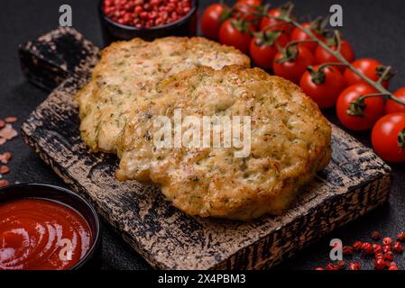 Délicieuses côtelettes de poulet hachées frites avec du sel, des épices et des herbes sur un fond de béton foncé Banque D'Images