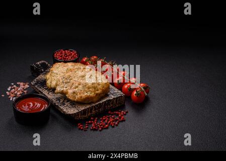 Délicieuses côtelettes de poulet hachées frites avec du sel, des épices et des herbes sur un fond de béton foncé Banque D'Images