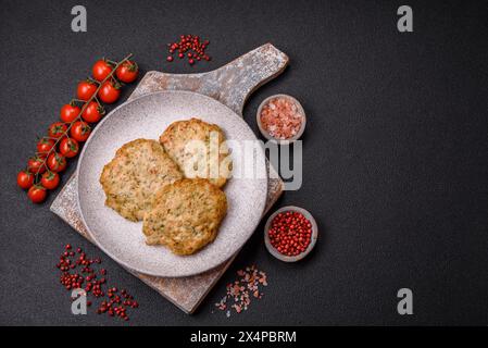 Délicieuses côtelettes de poulet hachées frites avec du sel, des épices et des herbes sur un fond de béton foncé Banque D'Images