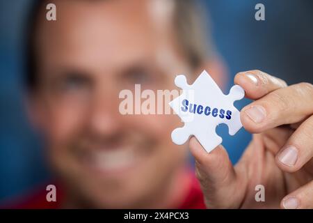 Un homme tenant une pièce de puzzle avec le mot succès écrit dessus. Concept d'accomplissement et de détermination Banque D'Images