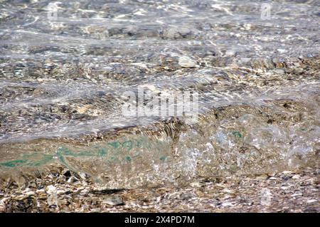 Découvrez la beauté fascinante de l'eau cristalline ondulant doucement le long d'un rivage rocheux. Cette image captivante capture l'harmonie tranquille Banque D'Images