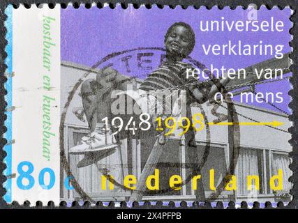 Timbre-poste oblitéré imprimé par les pays-Bas, qui célèbre le 50ème anniversaire des droits de l'homme : enfant dans un asile, vers 1998. Banque D'Images