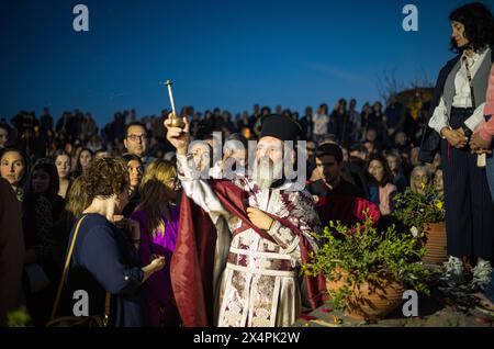 Monemvasia, Grèce, 3 mai 2024. Les fidèles de la ville médiévale de Monemvasia attendent d'entrer dans l'église de Chrysafitissa pour marquer le vendredi Saint dans l'église orthodoxe grecque. Ici, un prêtre orthodoxe sort de l'église pour asperger l'huile sainte sur les fidèles. (Tennessee Jones - Alamy Live News) Banque D'Images