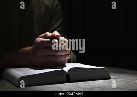 Religion. Homme chrétien priant sur la Bible à table, gros plan. Espace pour le texte Banque D'Images