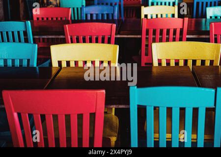 Dossiers de chaise colorés alignés sur les tables de restaurant sans clients au bar de plage Pompano Joe et restaurant à Miramar Beach, destin Florida, États-Unis. Banque D'Images